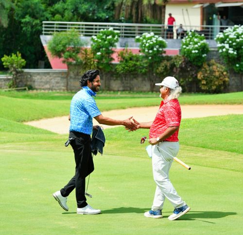 Two golfers shaking hands on a sunny day in Hyderabad, promoting friendship and sportsmanship.
